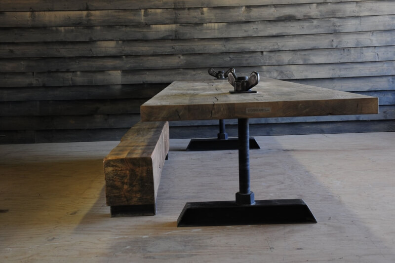 Houten tafel met unieke stalen poten en een massieve houten bankje