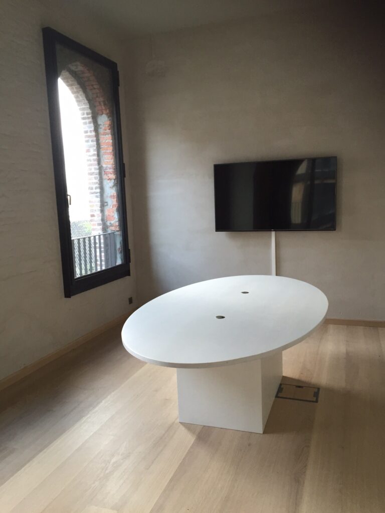 Strakke, moderne witte ovale tafel met een stevige vierkante basis en twee ronde openingen op het tafelblad.