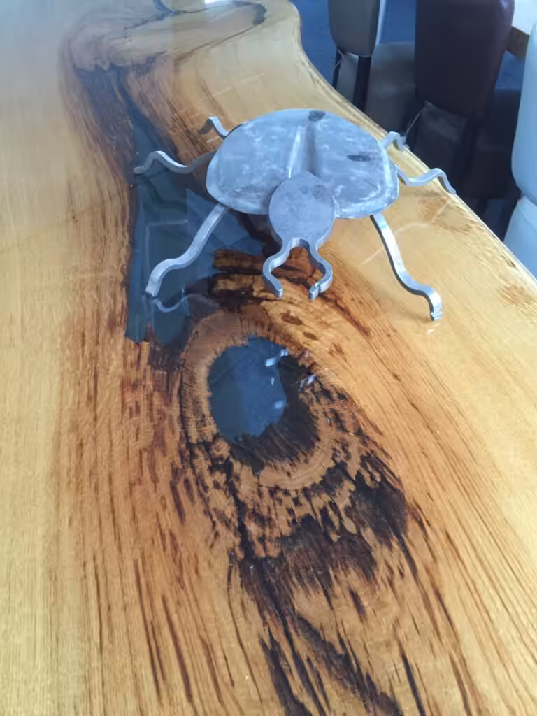 Staal kuntwerk op een houten tafel met een epoxylaag Staal kuntwerk op een houten tafel met een epoxylaag