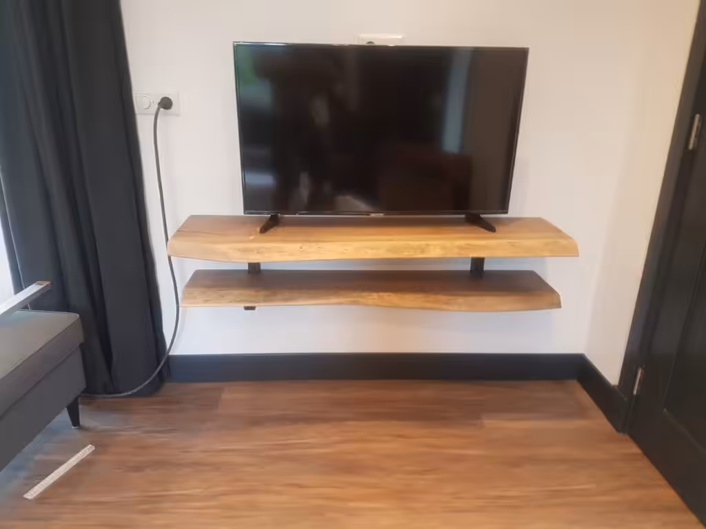 Houten tv-kast die aan de muur hangt Houten tv-kast die aan de muur hangt