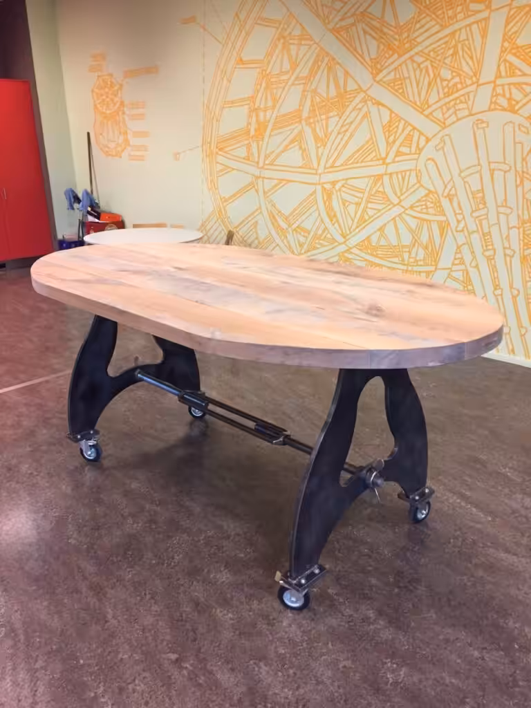 Ovalen houten tafel met stalen onderstel op wieltjes Ovalen houten tafel met stalen onderstel op wieltjes
