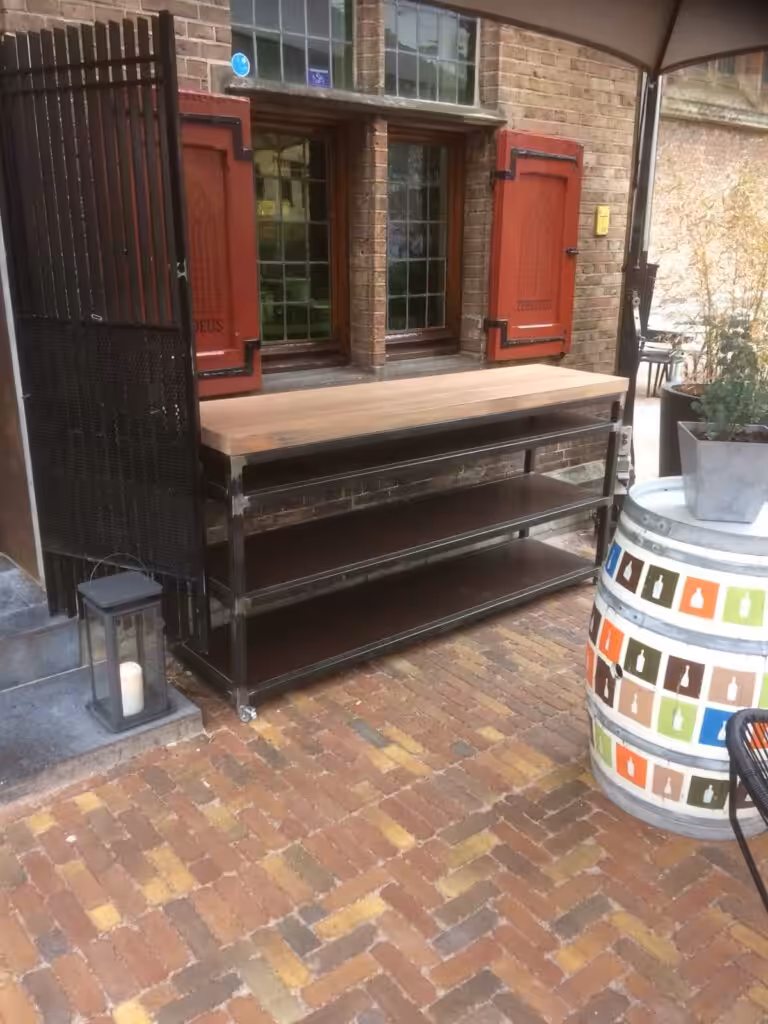 Stalen tafel op wieltjes met 3 stalen tussenplanken en 1 houten tafelblad Stalen tafel op wieltjes met 3 stalen tussenplanken en 1 houten tafelblad